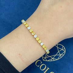 Fancy tennis bracelet with alternating yellow and white cushion cut diamonds.