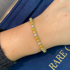 Fancy tennis bracelet with alternating yellow and white cushion cut diamonds.