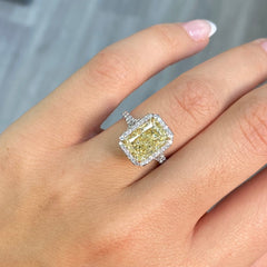 GIA certified light yellow elongated radiant diamond halo engagement ring with white diamonds.