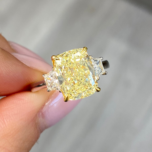 Unique engagement ring with an elongated yellow center diamond and two white diamonds on the sides.