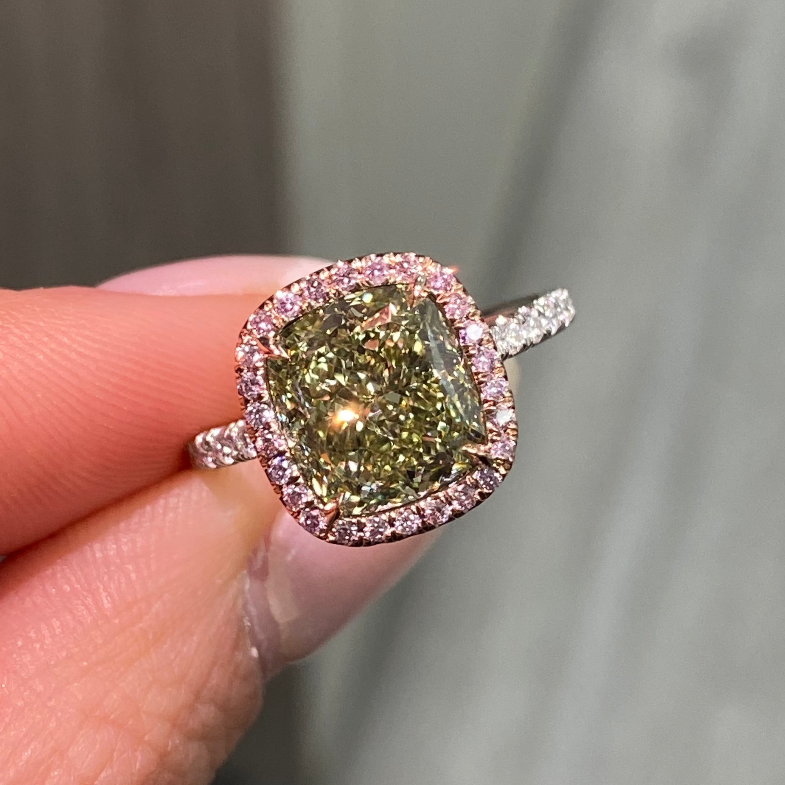 GIA certified greenish yellow cushion diamond in a pink halo engagement ring with VS1 clarity.