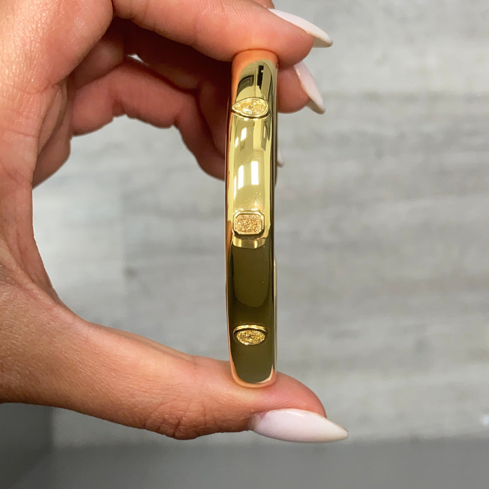 Unique bezel cuff bracelet with trio of yellow diamonds in radiant, oval, and pear shapes on a wide bangle.