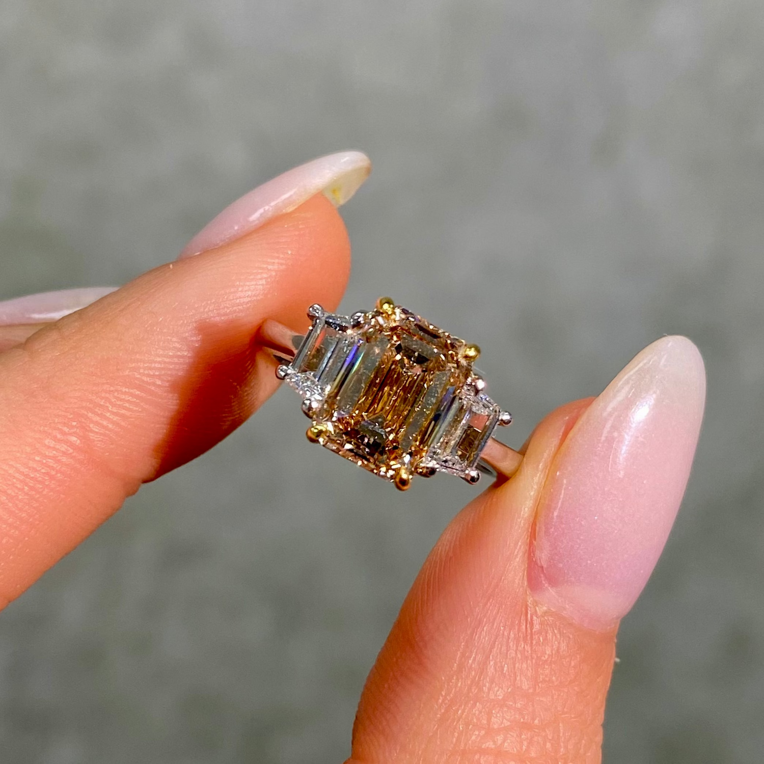 Hand holding a champagne emerald cut diamond ring 