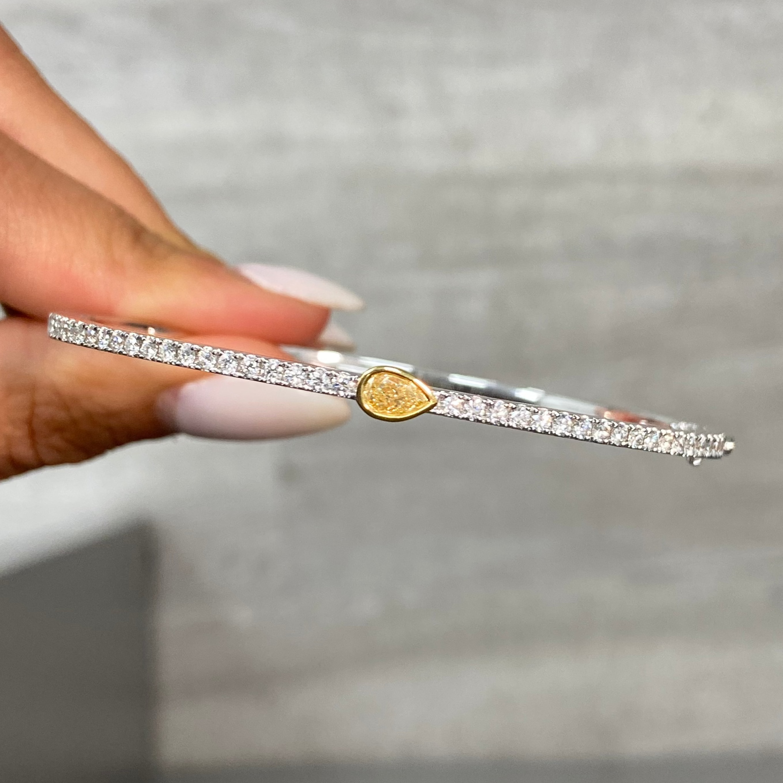 Fine Pear shaped yellow diamond bangle with light yellow pear and white round diamonds.