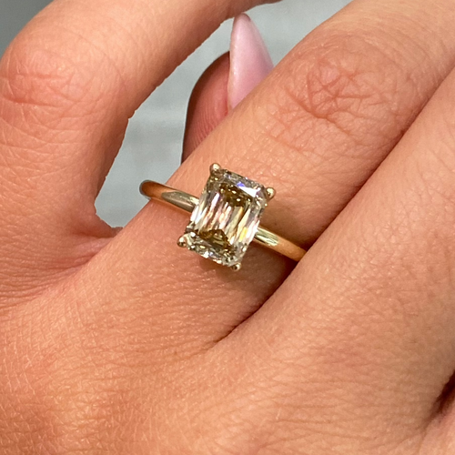Elegant fancy brown emerald cut diamond with an elongated shape and a golden champagne tone.