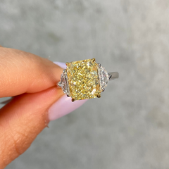 5.02 carat Yellow diamond ring held by a hand against a neutral background