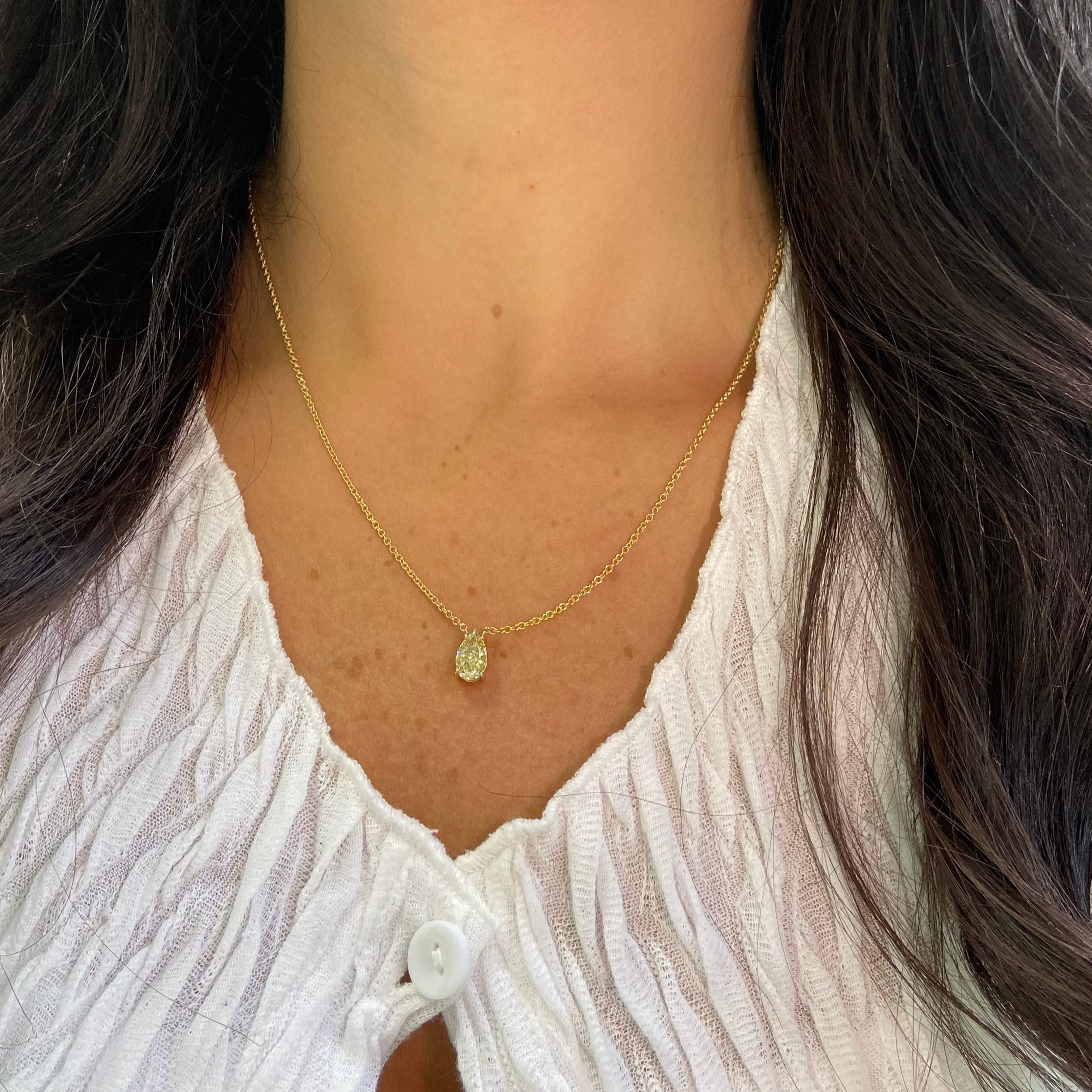 Gold necklace with a pear-shaped fancy yellow diamond pendant  worn by female 
