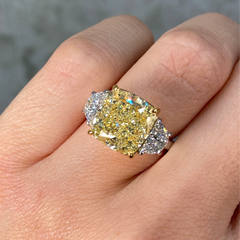 7 carat yellow diamond ring with two white diamonds on a female hand