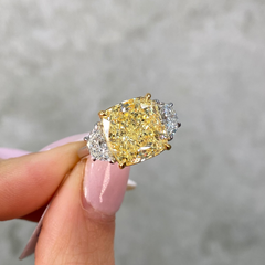 7 carat yellow diamond ring with two white diamonds held by female 