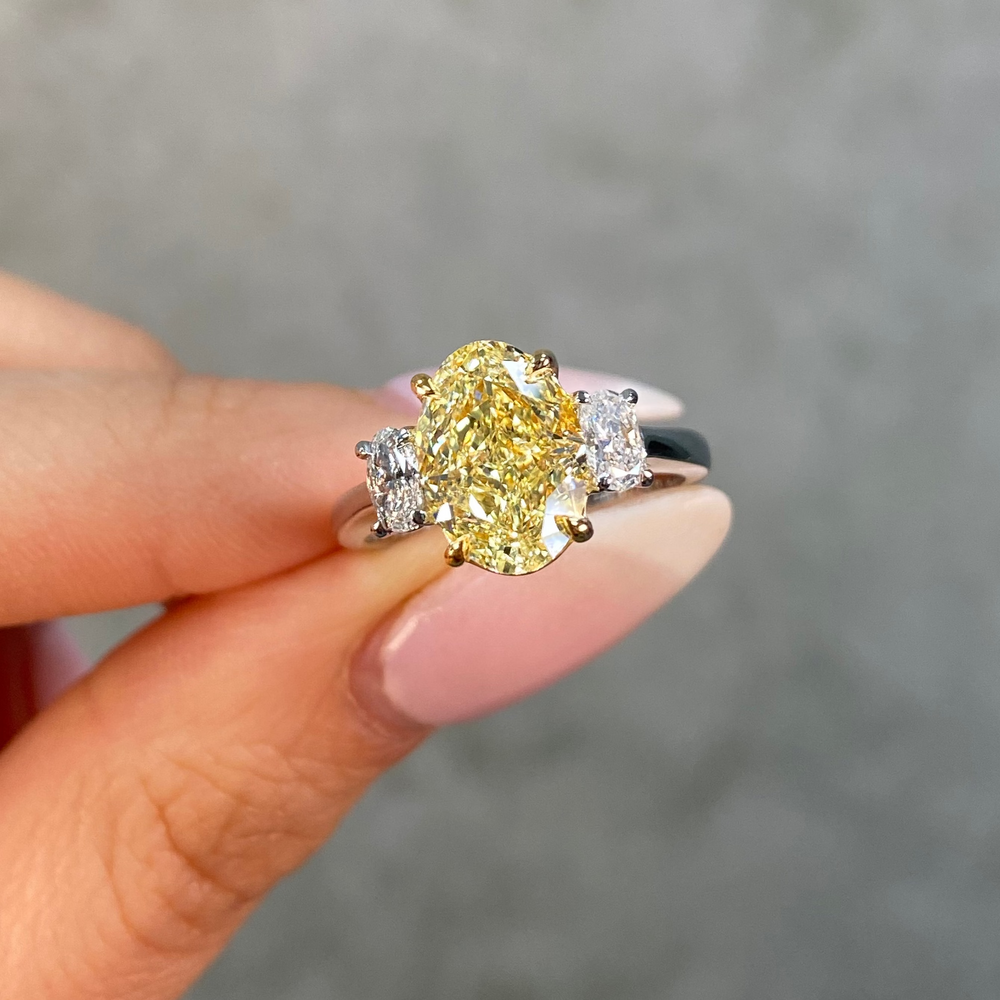 Ring with a oval yellow diamond and two smaller diamonds on a female hand