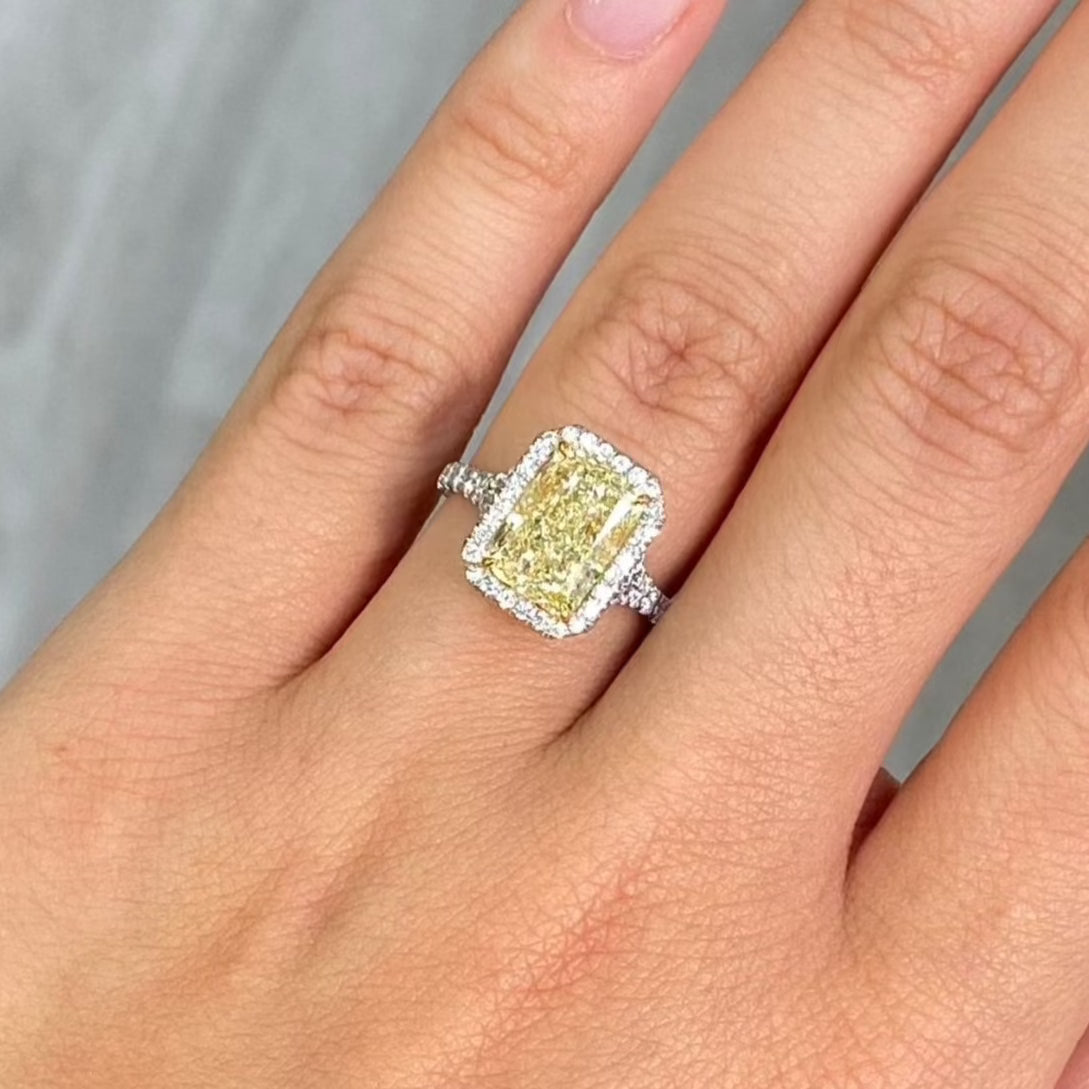 GIA certified light yellow elongated radiant diamond halo engagement ring with white diamonds.