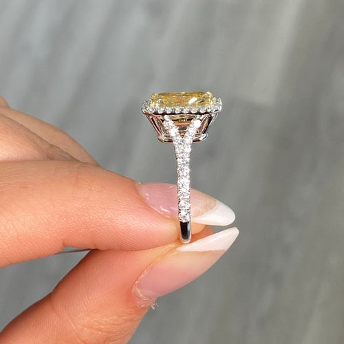 GIA certified light yellow elongated radiant diamond halo engagement ring with white diamonds.