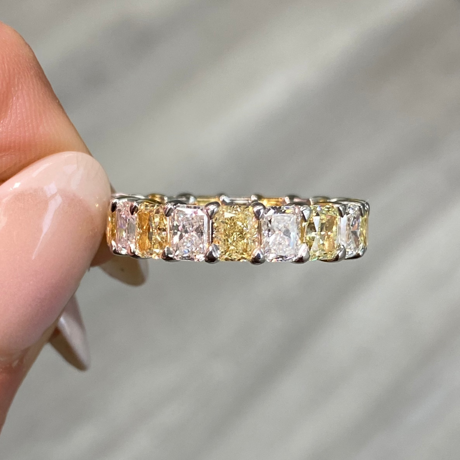 Elegant yellow and white radiant cut diamond eternity band featuring VS-VVS clarity.