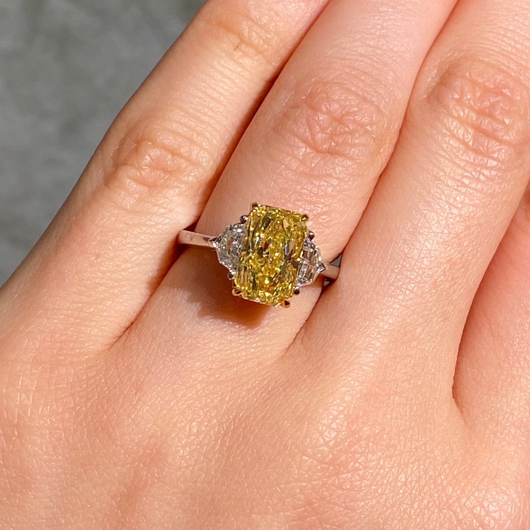 Fancy intense yellow elongated radiant cut ring female hand