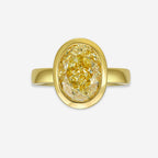 Gold bezel ring with a yellow diamond on a white background