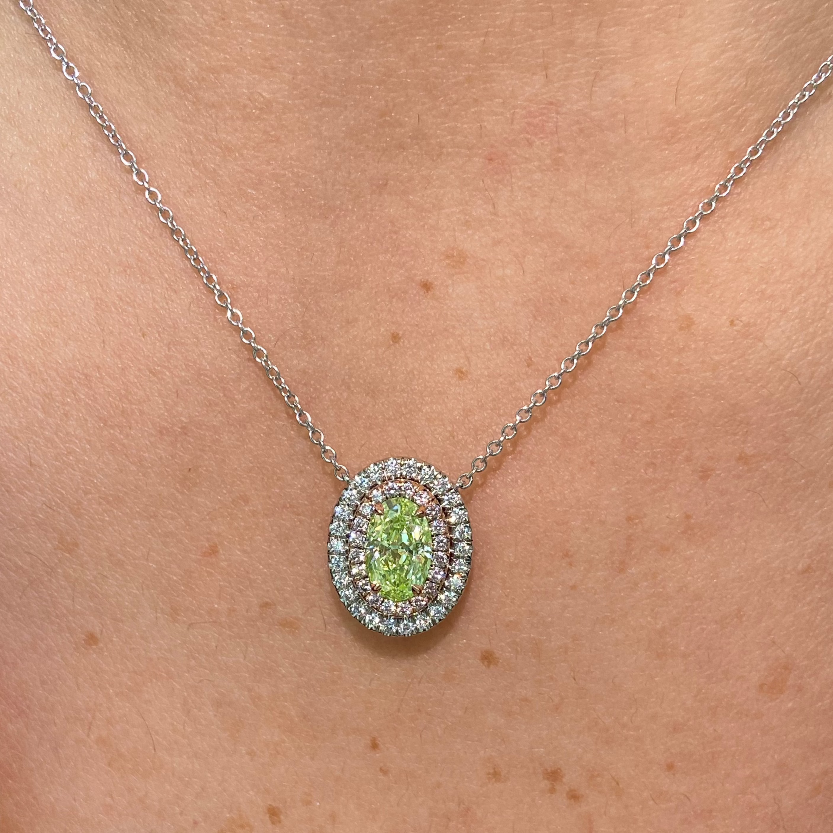 Fancy yellow-green oval diamond pendant with a double halo design and SI1 clarity.