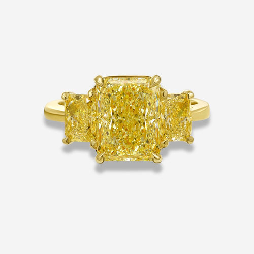 Yellow diamond three stone ring on a white background