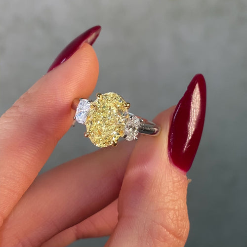 video of Ring with an oval yellow diamond and two smaller diamonds on a white background