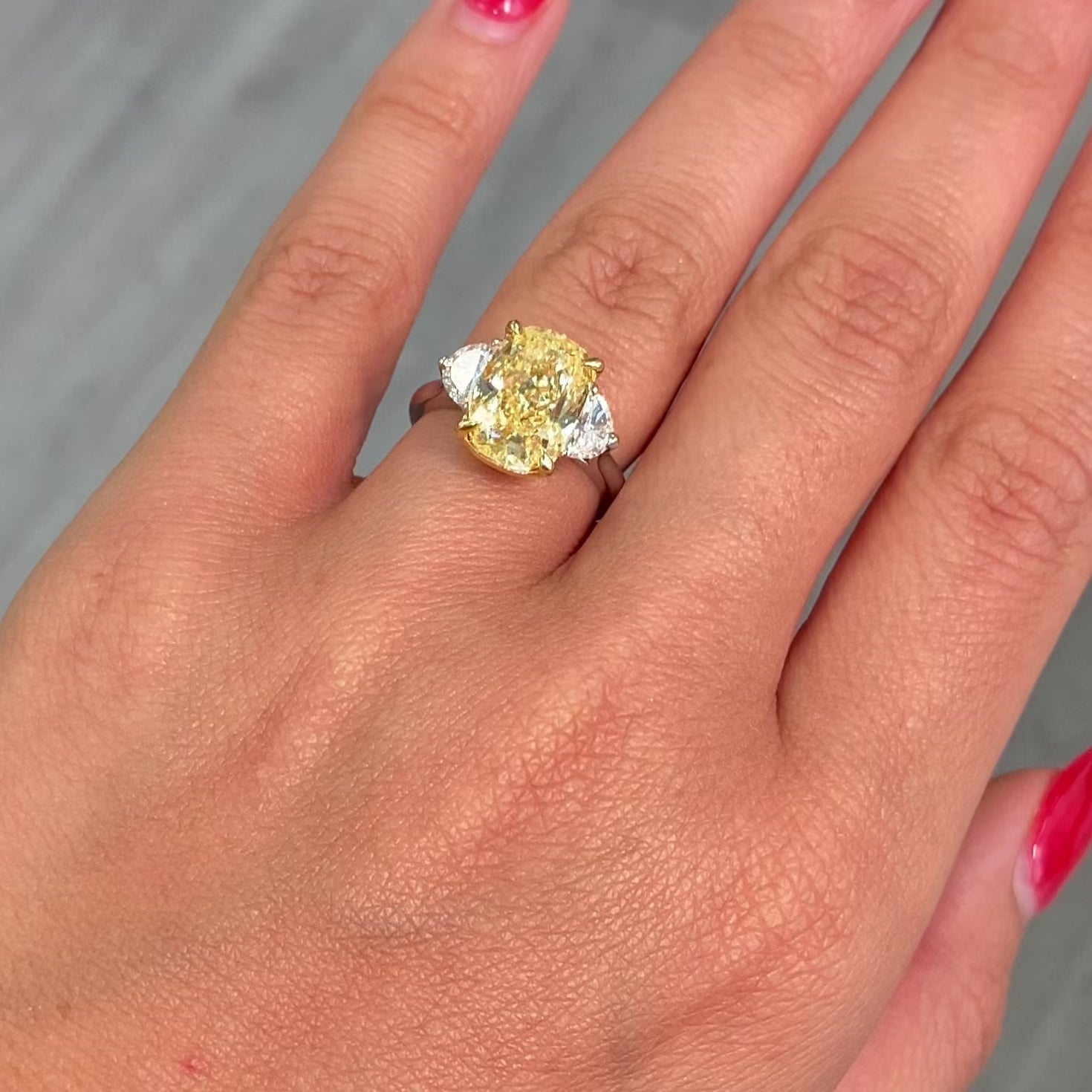 Unique Three-stone ring featuring a GIA-certified fancy yellow elongated cushion diamond with VVS2 clarity.