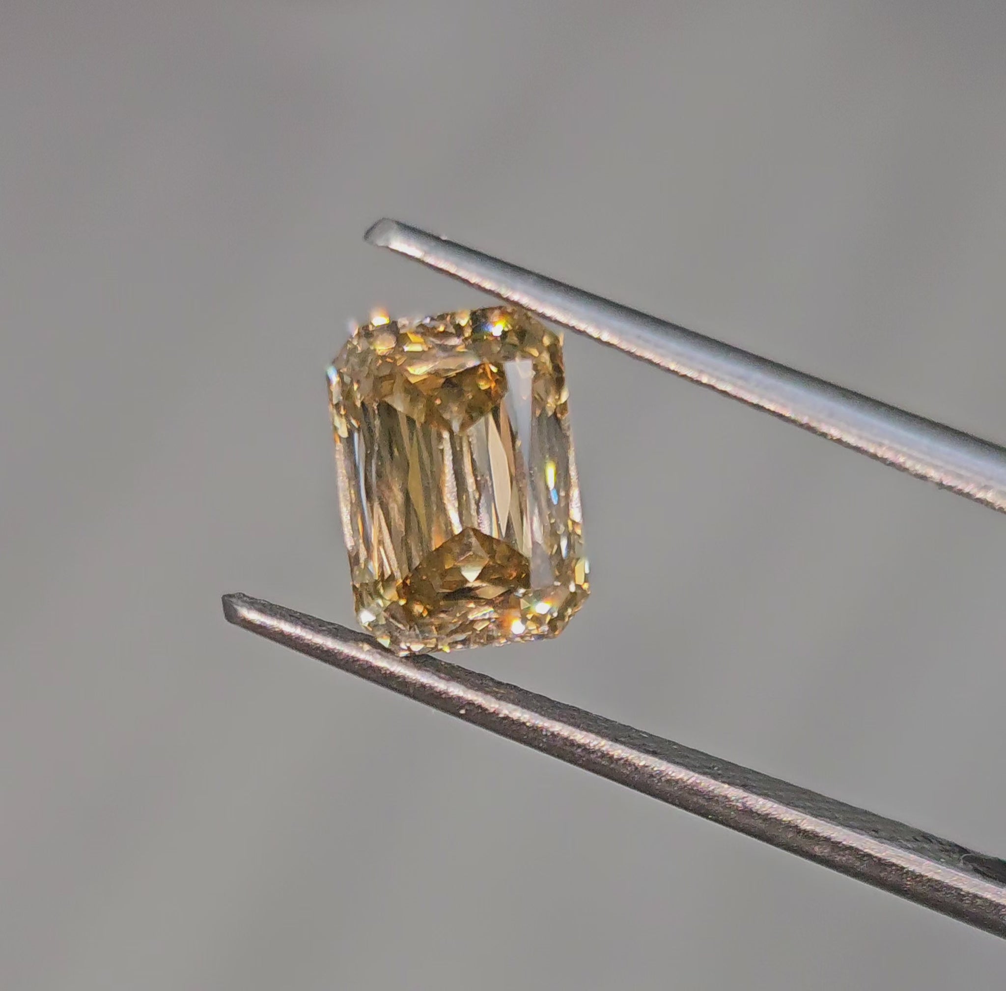 Elegant fancy brown emerald cut diamond with an elongated shape and a golden champagne tone.
