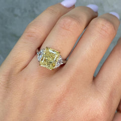 video of fancy yellow diamond ring held by a hand against a gray background