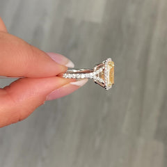 GIA certified light yellow elongated radiant diamond halo engagement ring with white diamonds.