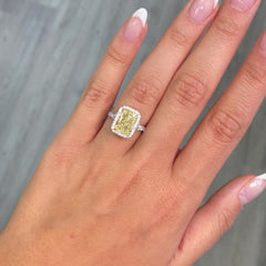 GIA certified light yellow elongated radiant diamond halo engagement ring with white diamonds.