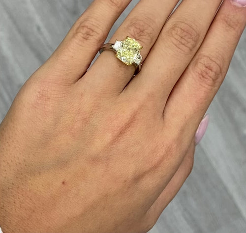 Unique engagement ring with an elongated yellow center diamond and two white diamonds on the sides.
