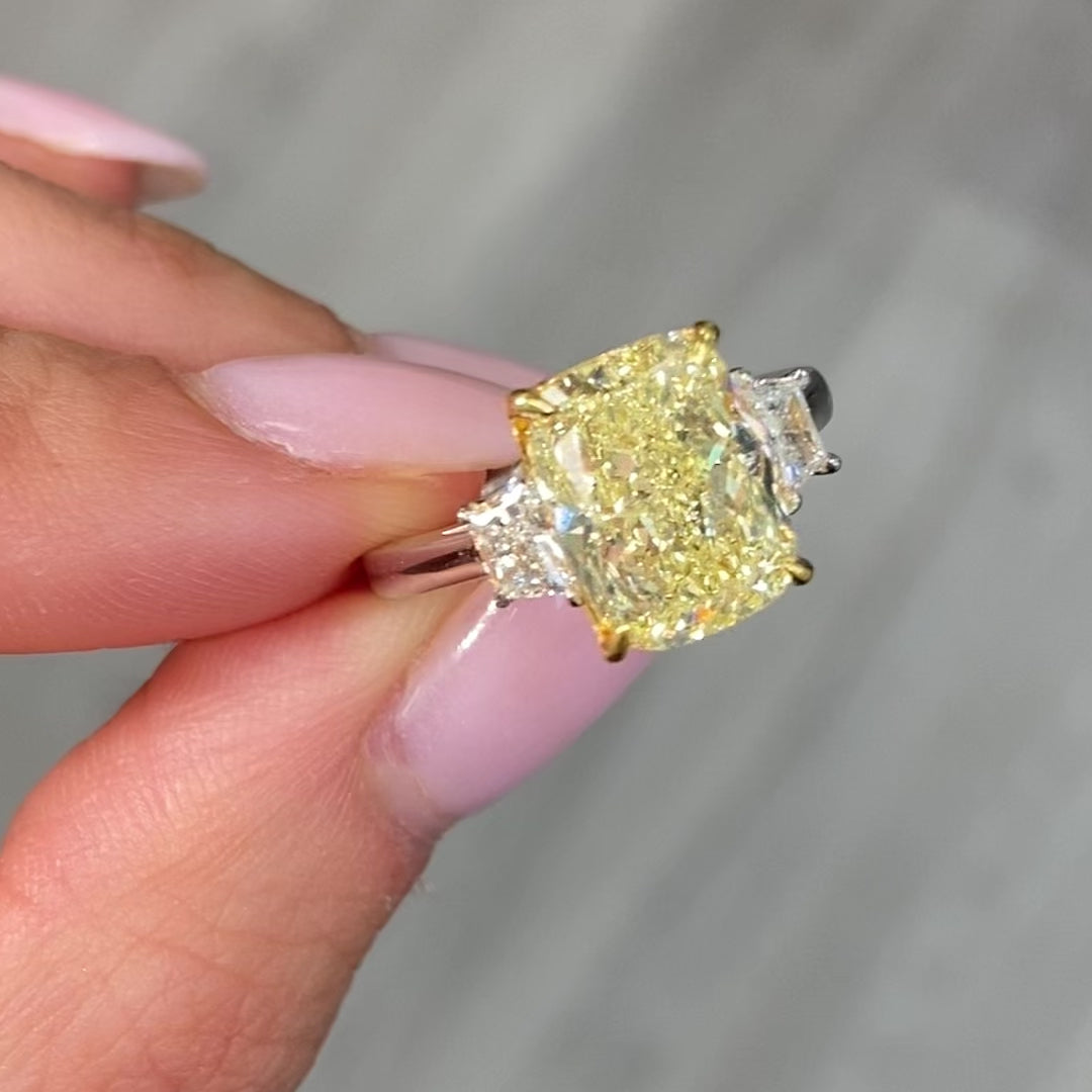 Unique engagement ring with an elongated yellow center diamond and two white diamonds on the sides.