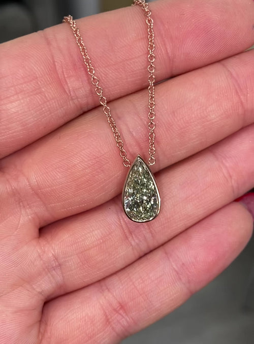 Stunning green pear-shaped diamond pendant in a pink bezel setting with SI1 clarity.
