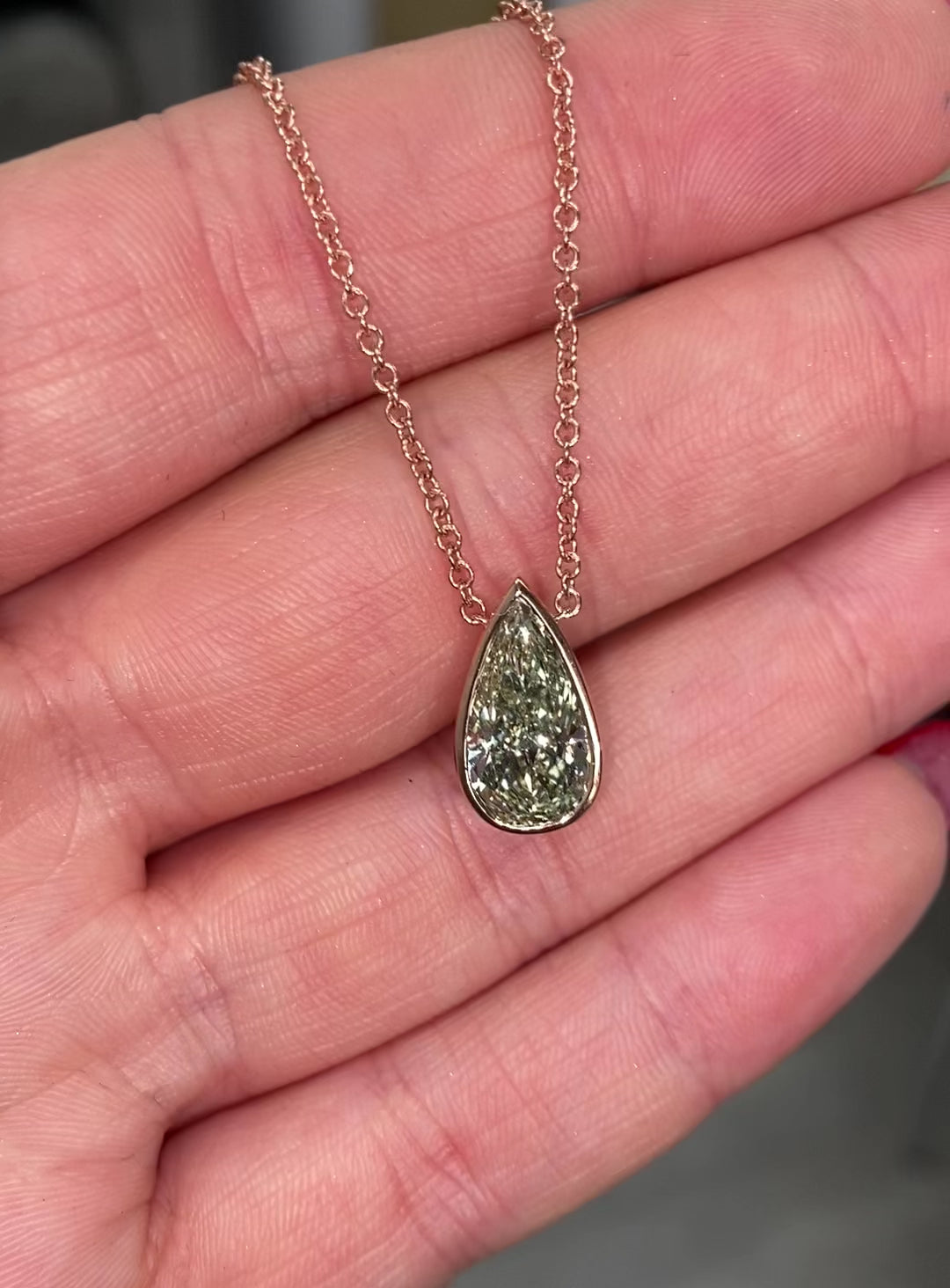 Stunning green pear-shaped diamond pendant in a pink bezel setting with SI1 clarity.