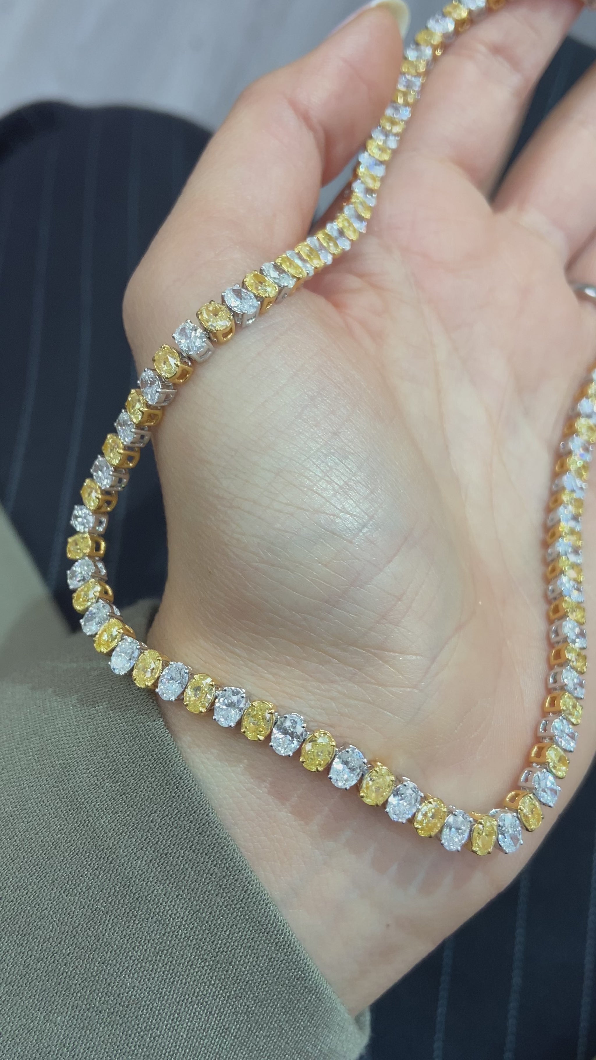 Video of Necklace with yellow and white oval diamonds held by female 